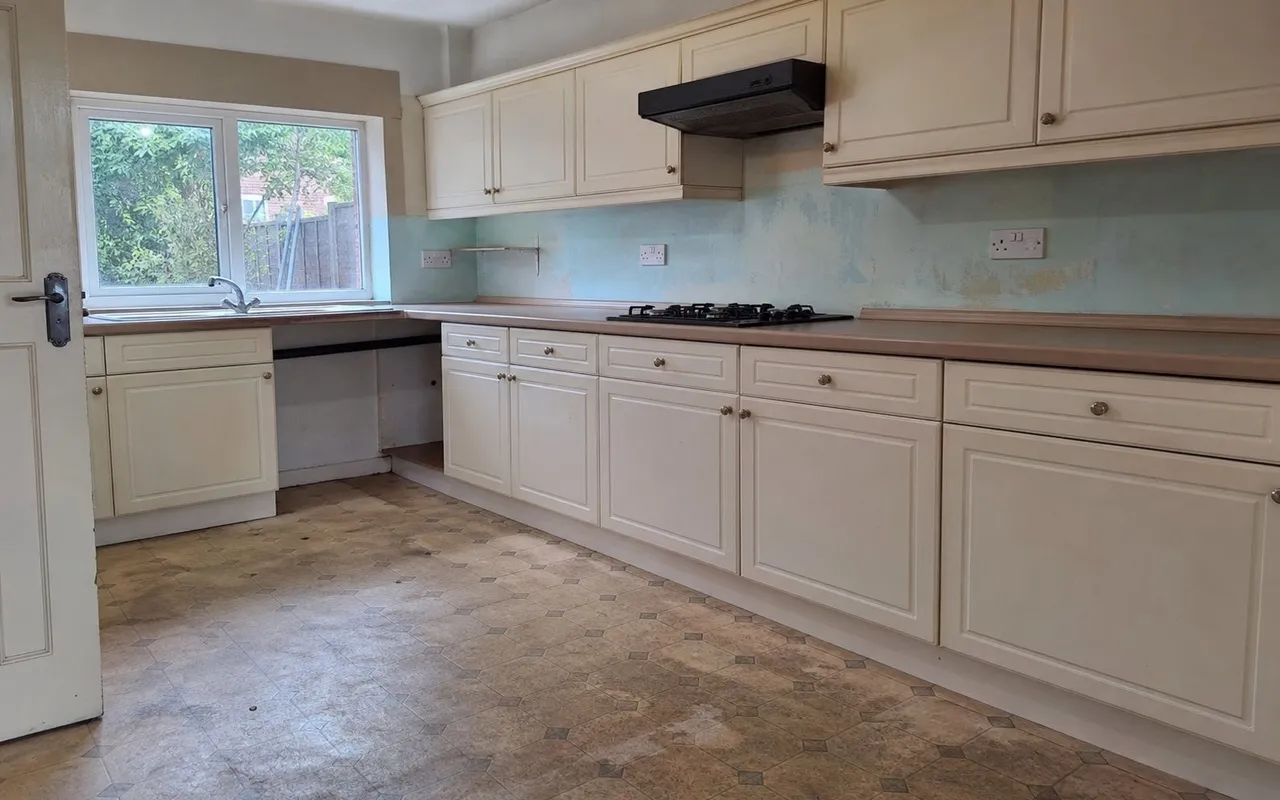 Kitchen before works: worn lino flooring and dated splashback